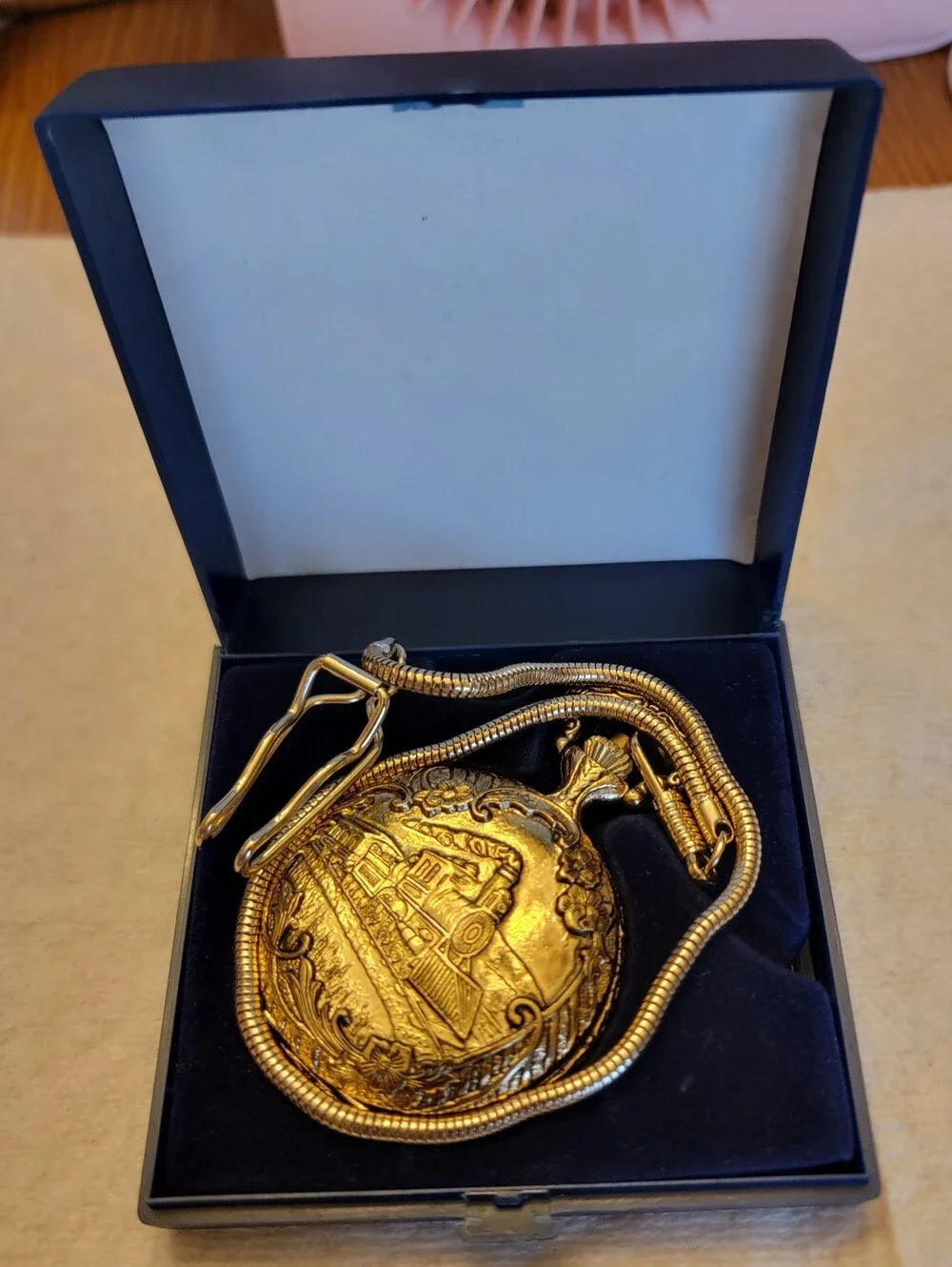 Vintage gold-tone pocket watch has a raised steam engine train motif.